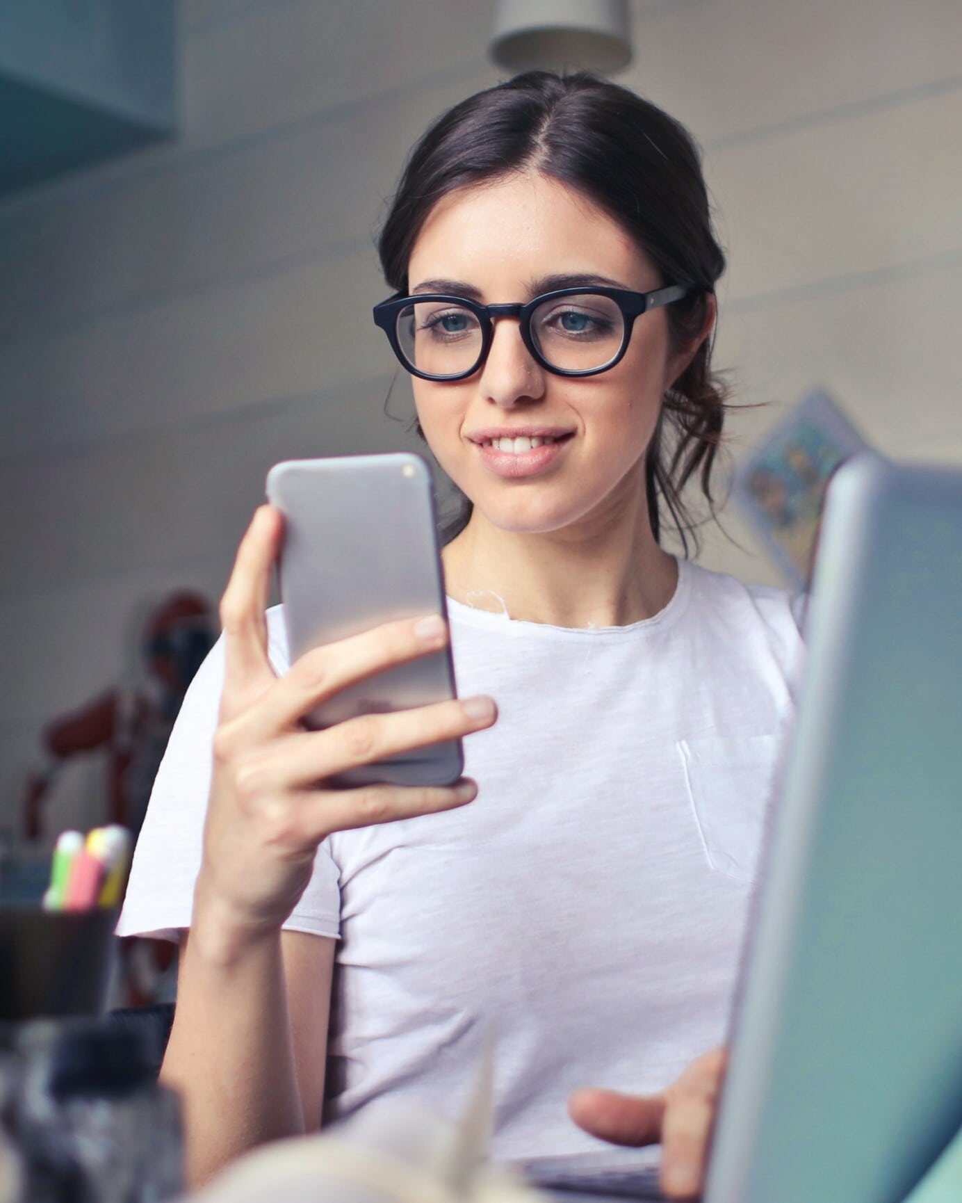 Žena s okuliarmi používajúca notebook a smartfón súčasne.
